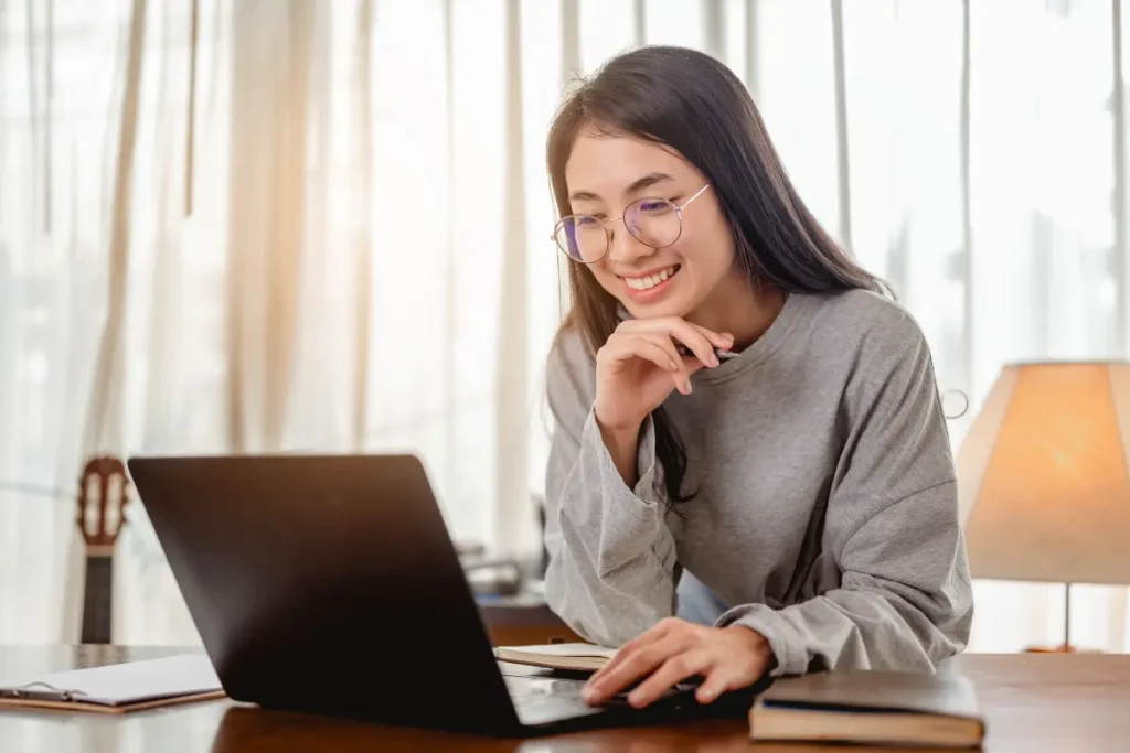 A woman smiling while browsing on her laptop.