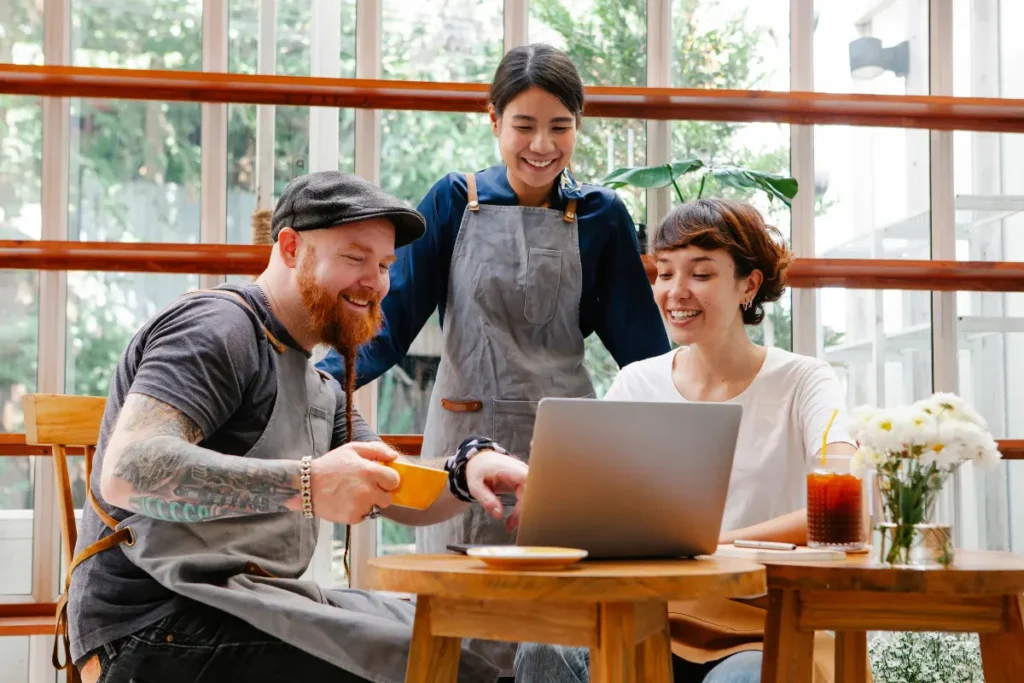 Three colleagues smiling in front of a laptop.