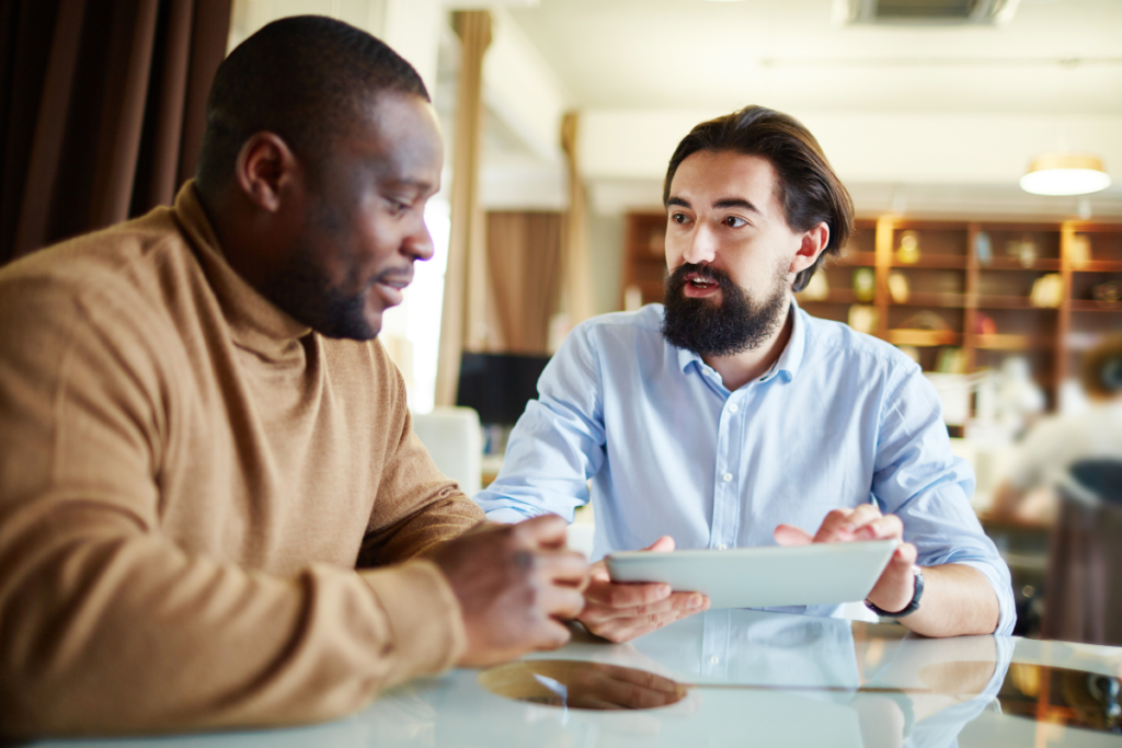 Two men discuss work while holding a tablet.