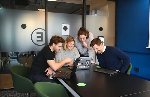 Colleagues happily discussing surrounding a laptop