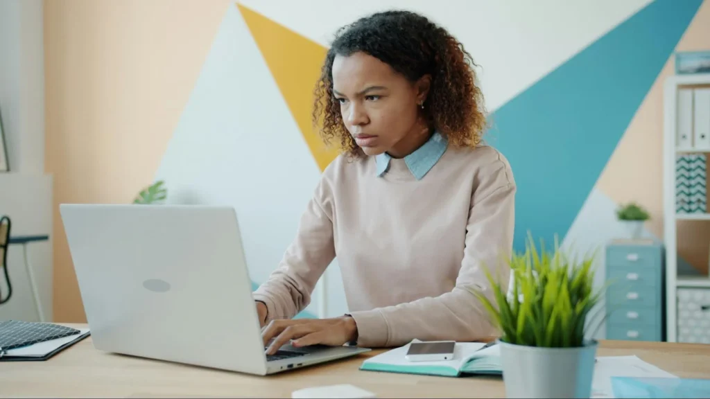 Person typing on a laptop while working at a wooden desk.