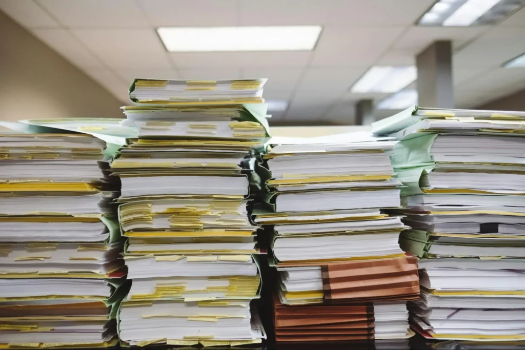 Large stack of paperwork and folders piled high on a desk.