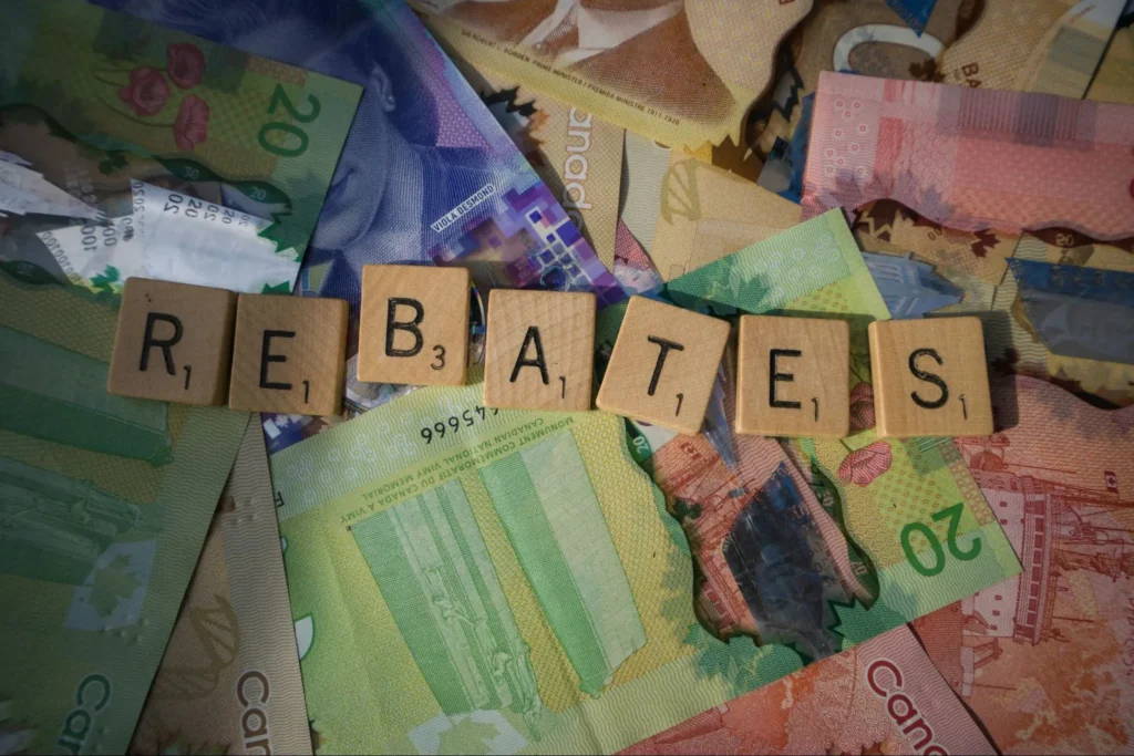 Wooden blocks spelling “REBATES” surrounded by currency notes.