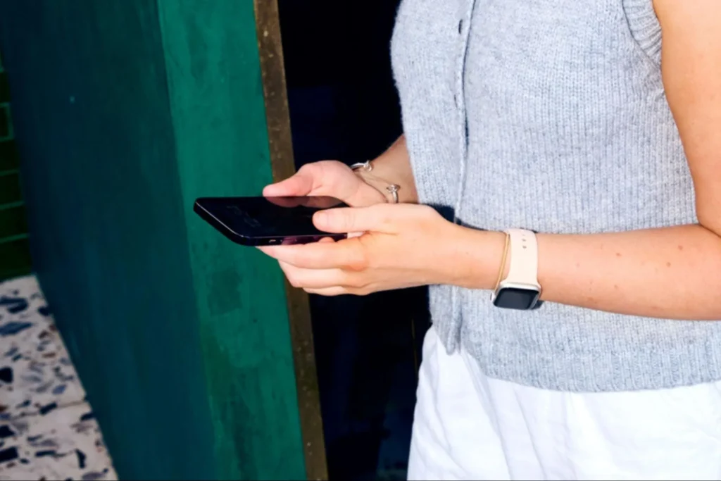 Woman using smartphone while wearing smartwatch.