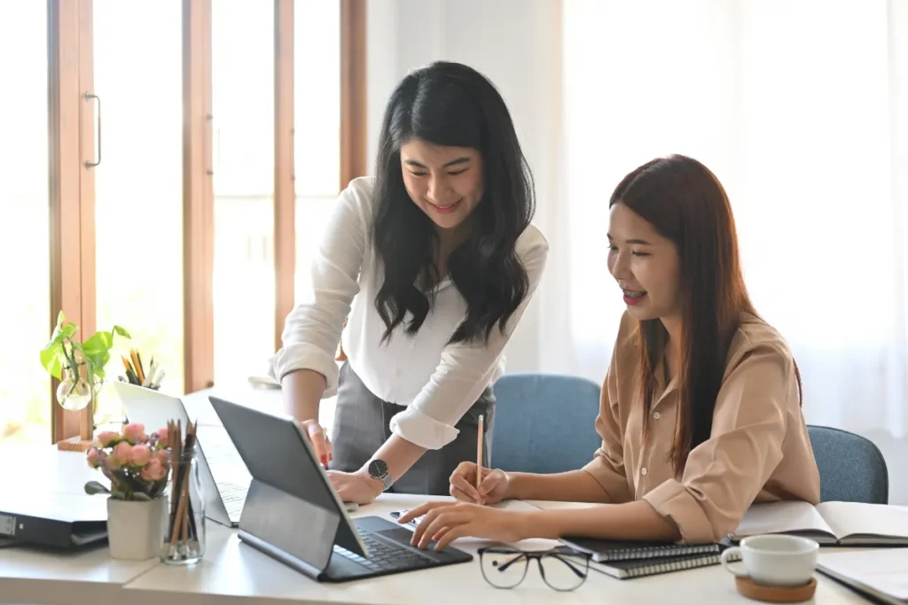 A colleague watching over another colleague's laptop