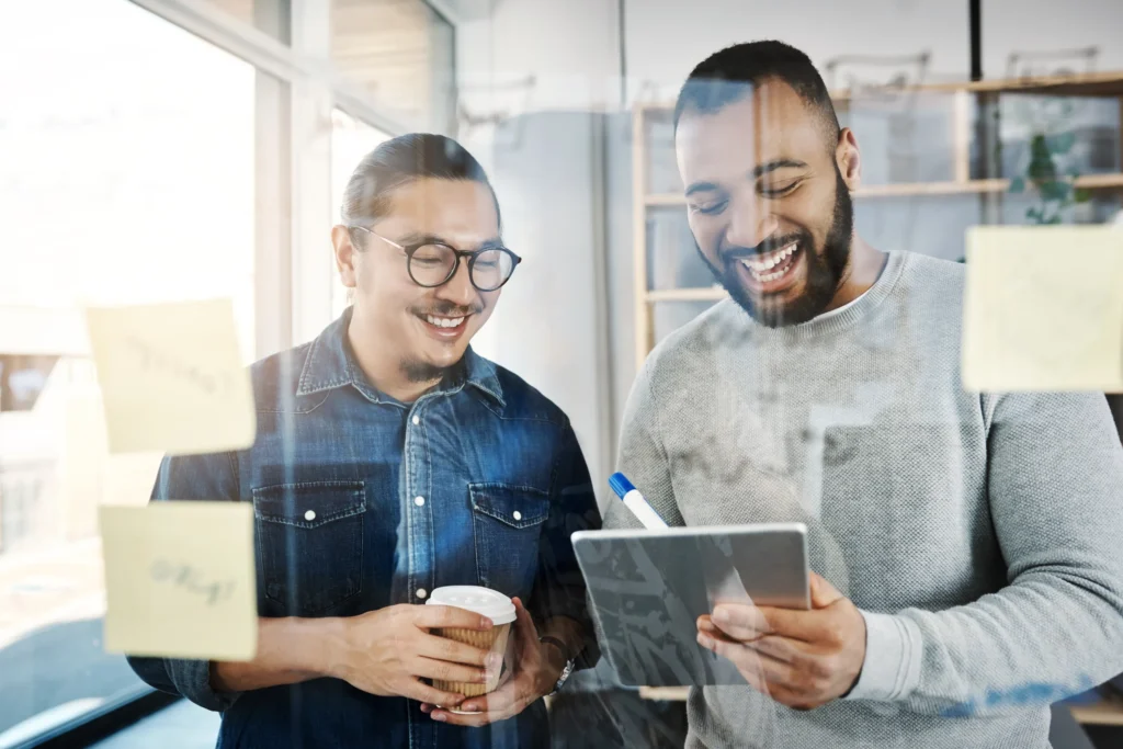 Two coworkers smiling and collaborating with a tablet, illustrating teamwork supported by the best HR software