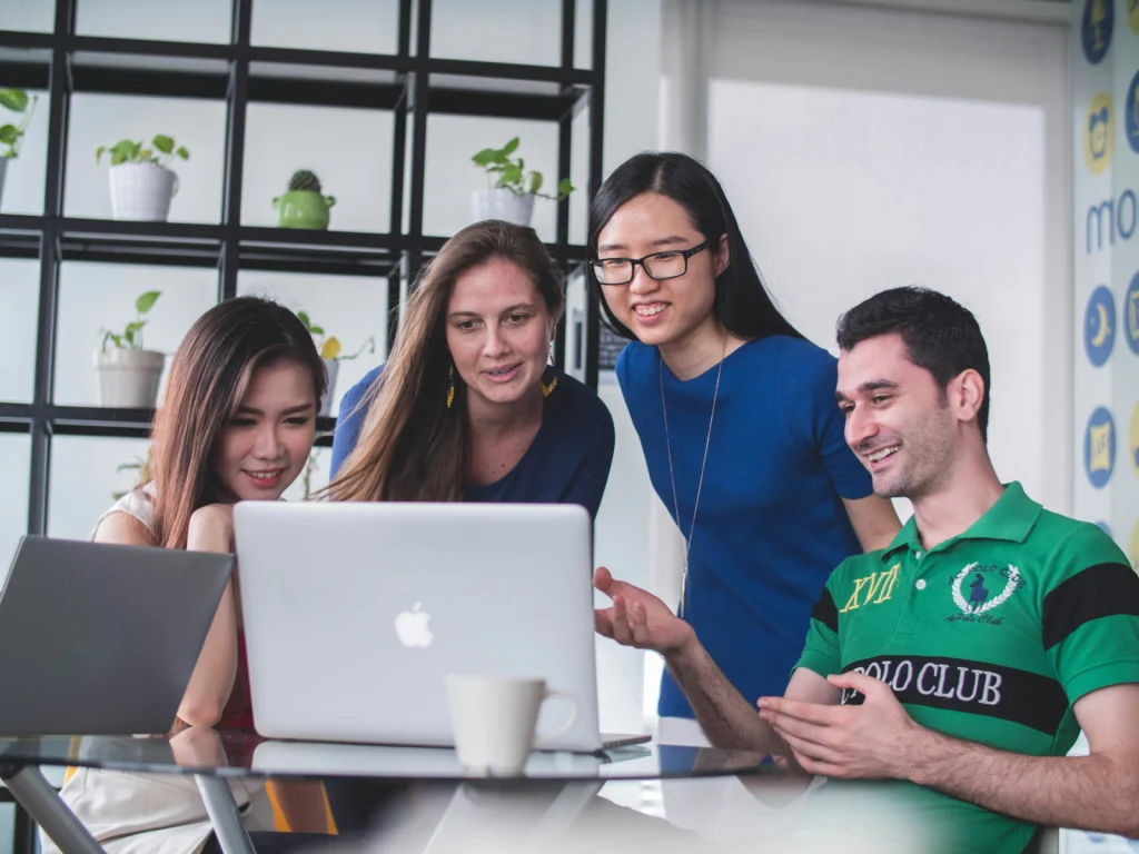 Colleagues hovering a laptop while discussing