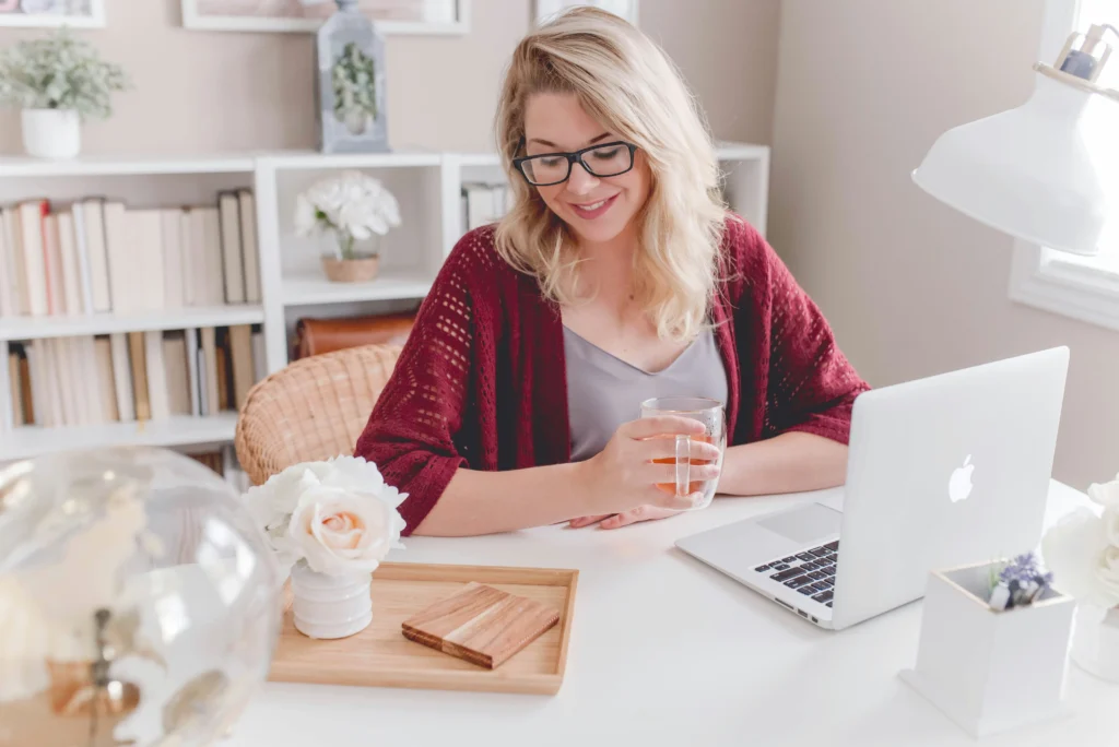 An image of a woman working on a laptop in a sunlit room