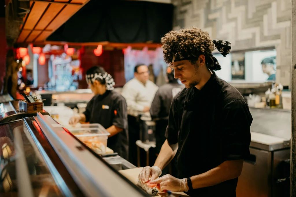A chef skillfully preparing sushi at a restaurant, showcasing fresh ingredients and precise techniques.