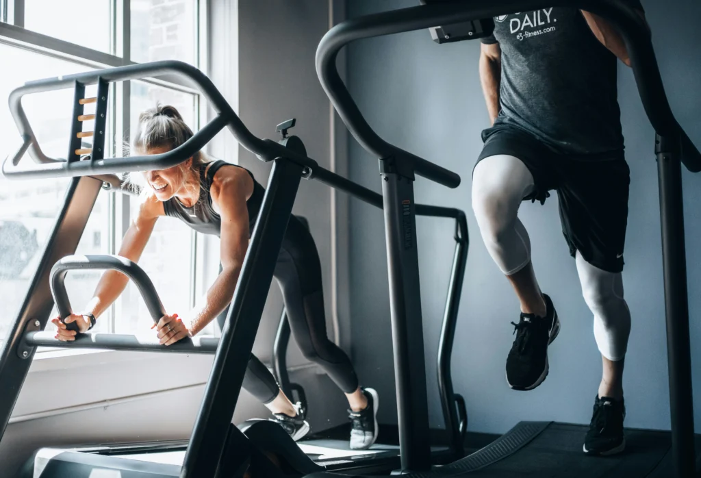 A man and woman exercise on treadmills in a gym, focused on their workout routines.