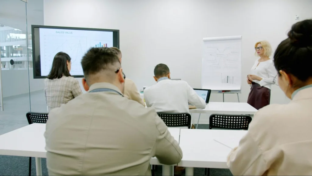 Team members collaborating in a meeting room, with a whiteboard displaying notes and ideas in the background
