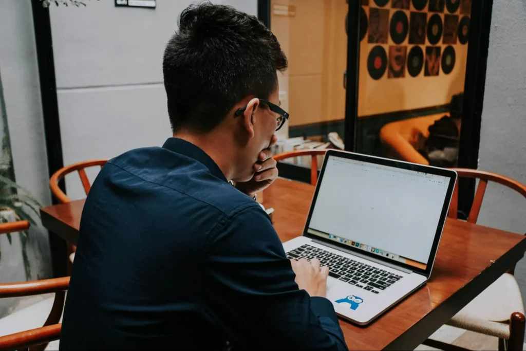 A focused professional looking thoughtfully at a laptop screen, illustrating an employee exploring new tools and concepts from a beginner's guide to AI at work.