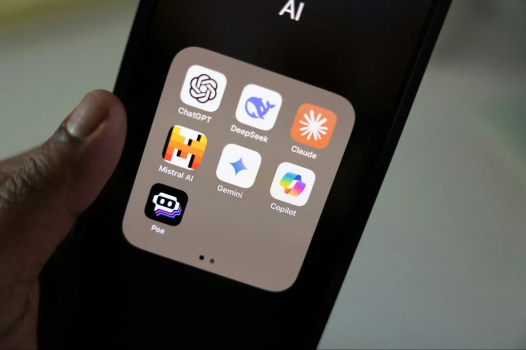 A close-up of a smartphone screen displaying a folder of popular AI apps like ChatGPT, Claude, and Gemini, highlighting the accessible tools covered in a beginner's guide to AI at work.