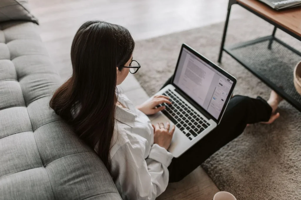 Woman sitting on the couch, typing on her laptop