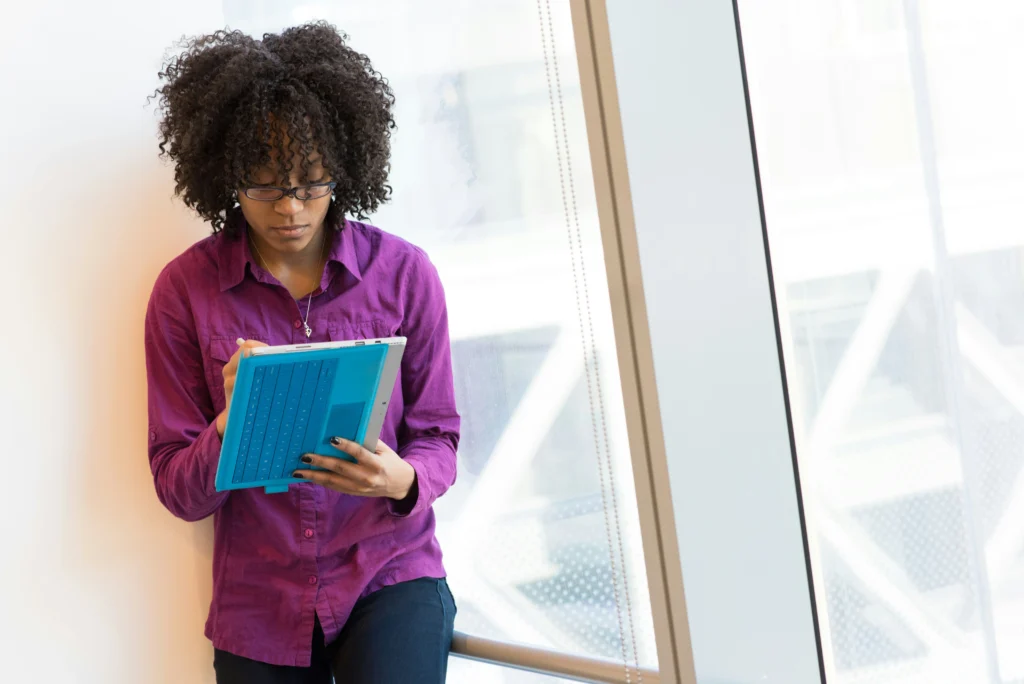 A woman holding a tablet in her hands, focused on the screen.