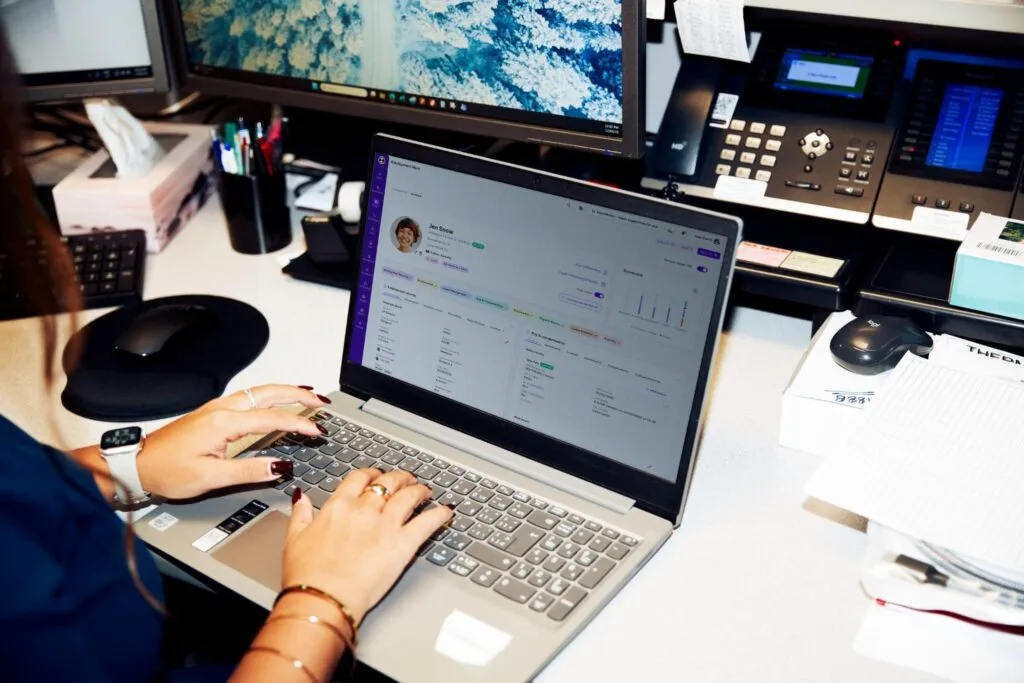 An HR professional working on a laptop at a desk, viewing an employee profile on the Employment Hero HRIS software dashboard, illustrating how Canadian small businesses easily manage their daily HR tasks.