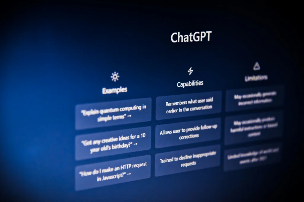 Close-up view of a computer monitor displaying the ChatGPT homepage user interface, showing columns for Examples, Capabilities, and Limitations.