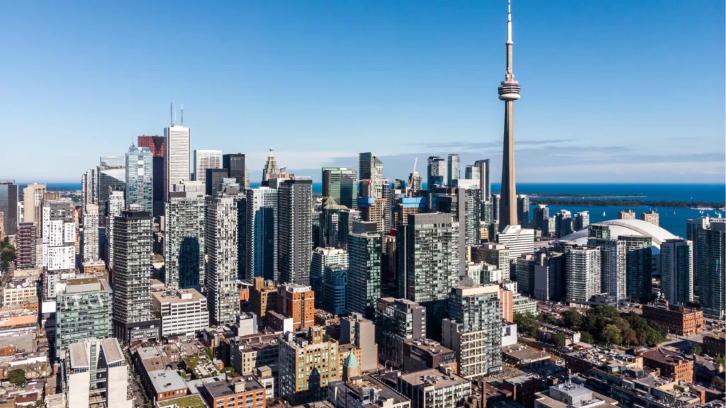 Aerial view of Toronto's downtown skyline featuring the CN Tower, skyscrapers, and Lake Ontario on a clear day