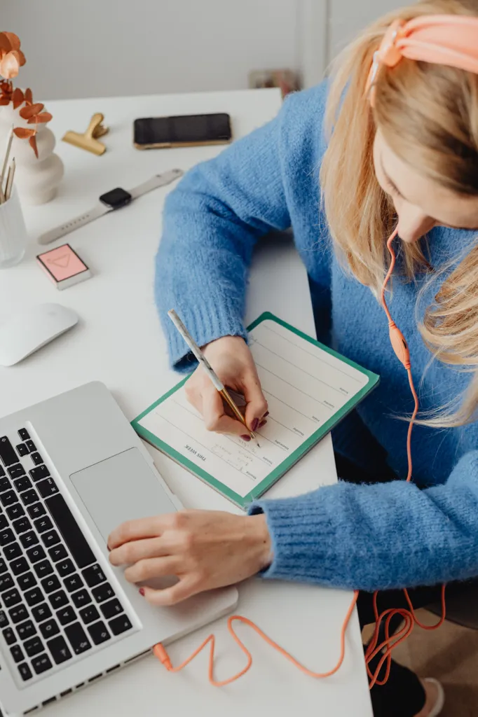 Woman writing while scrolling on her laptop