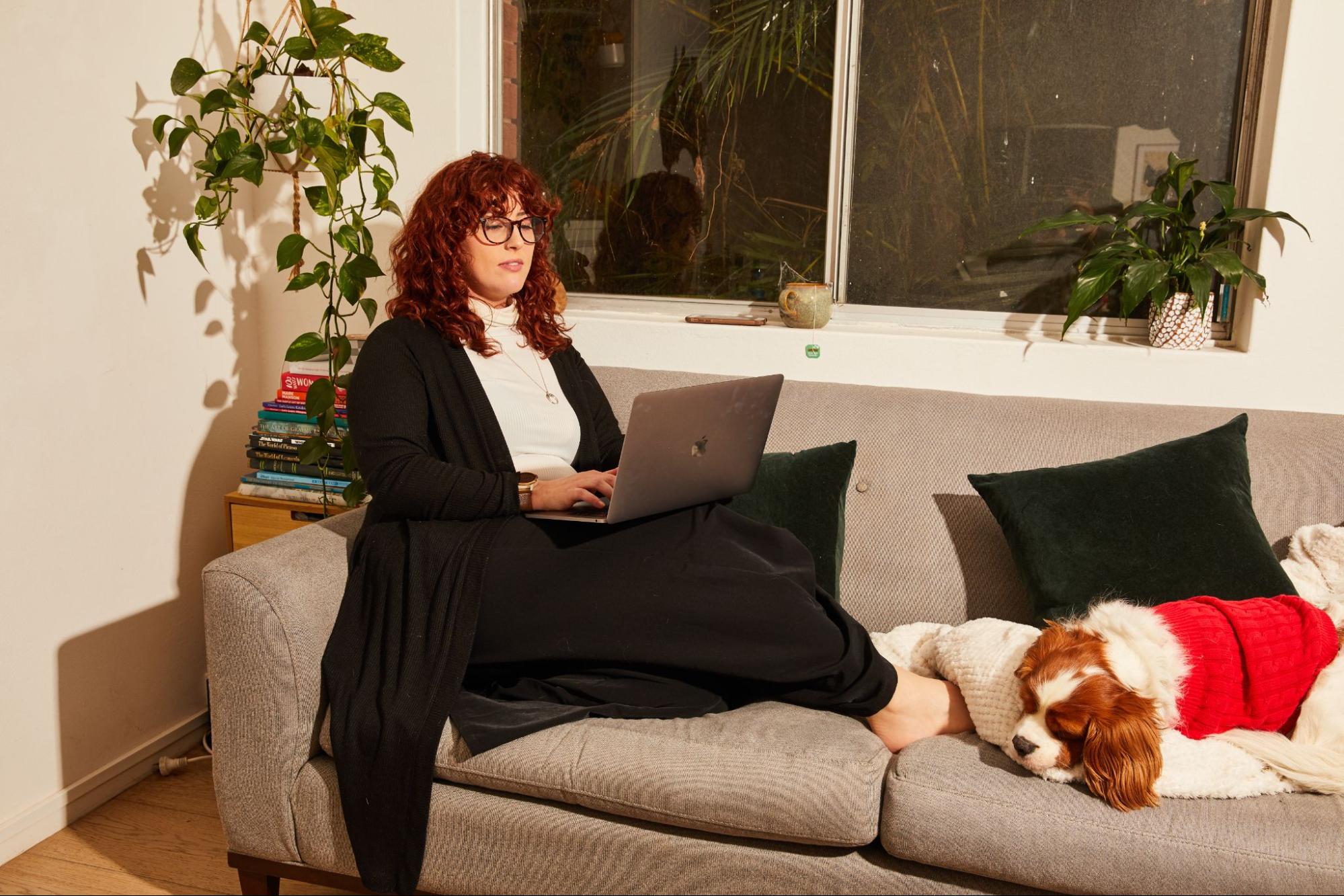 employee working from home on her sofa with her dog