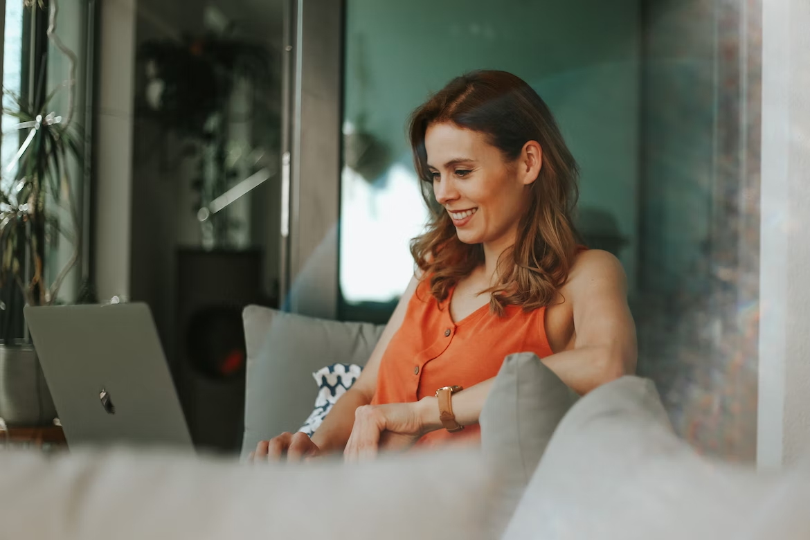 woman smiling while using her laptop at home