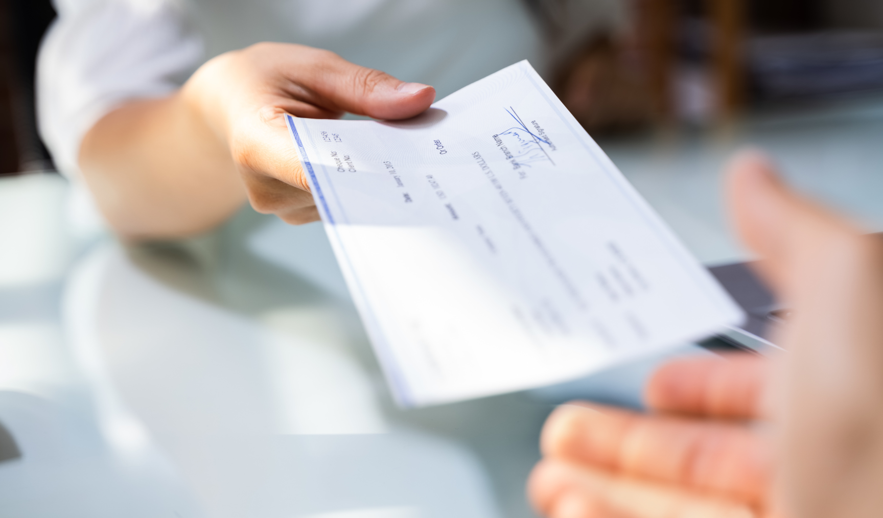 closeup of a hand passing a cheque to someone else