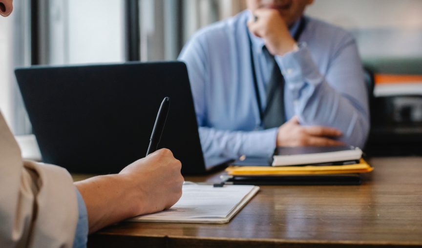 two colleagues talking to each other at a desk