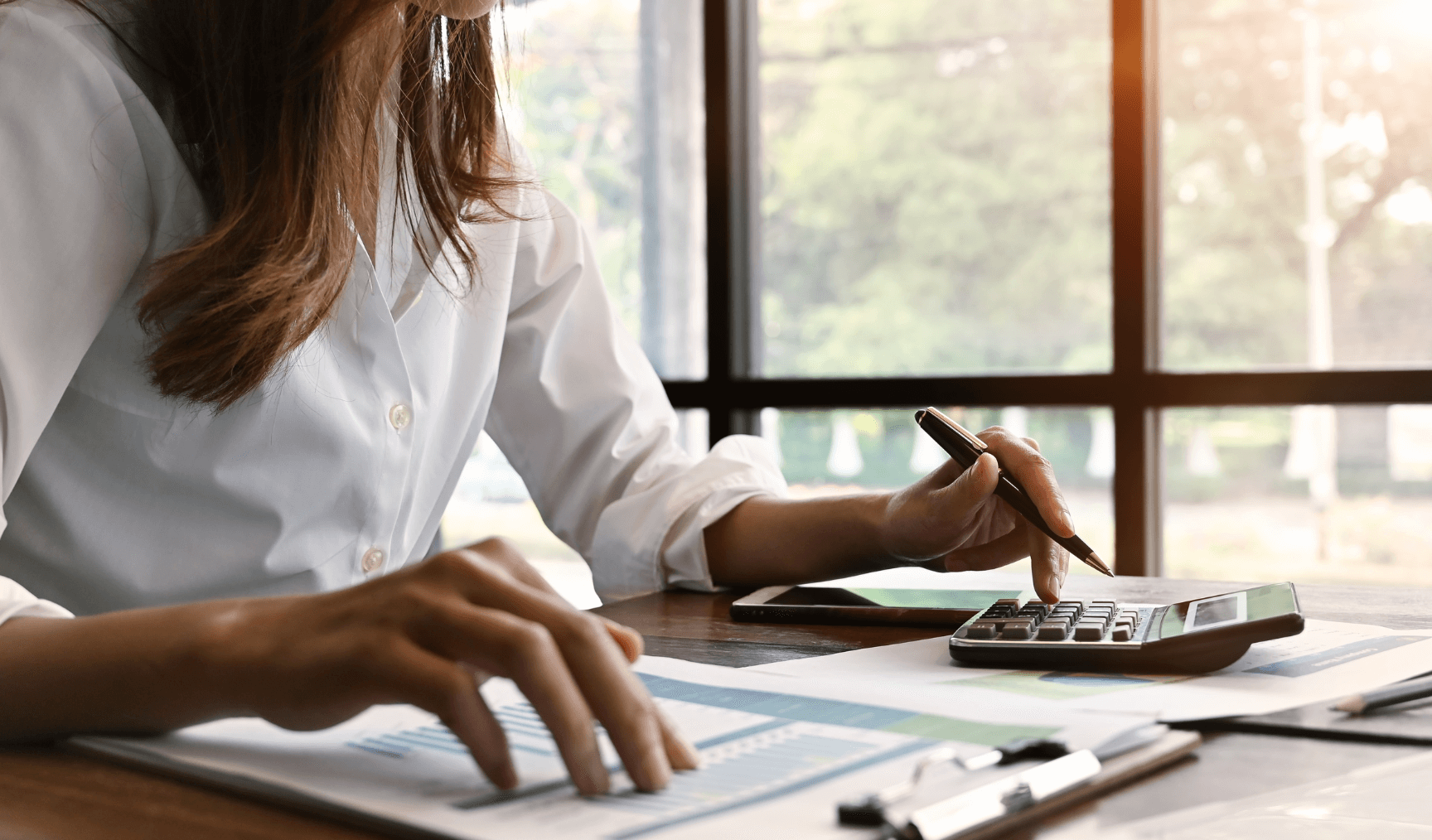 woman calculating numbers with a calculator and referring to her documents