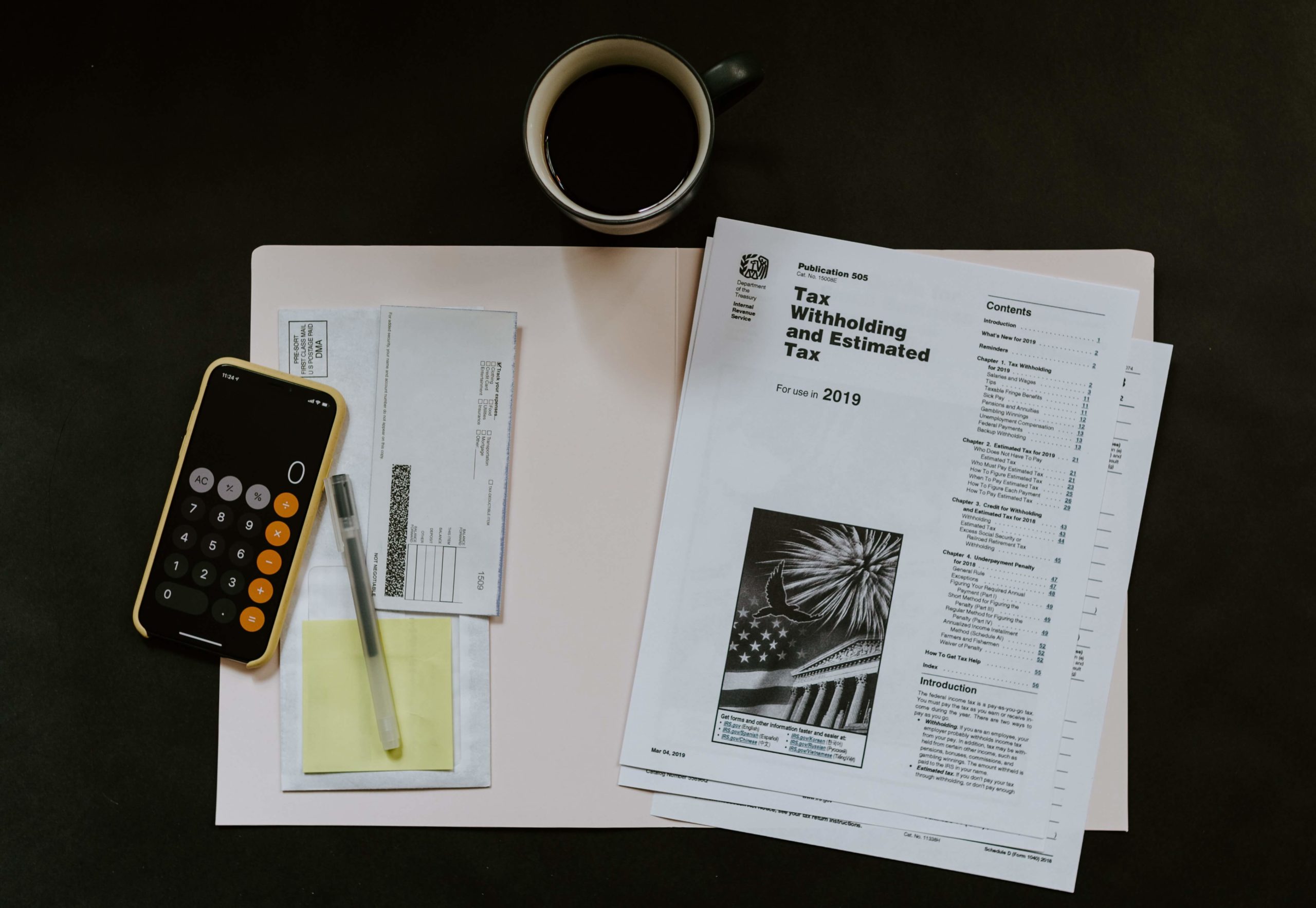 A desk scene with tax documents, a calculator, a pen, and a coffee cup, representing a financial or tax preparation workspace