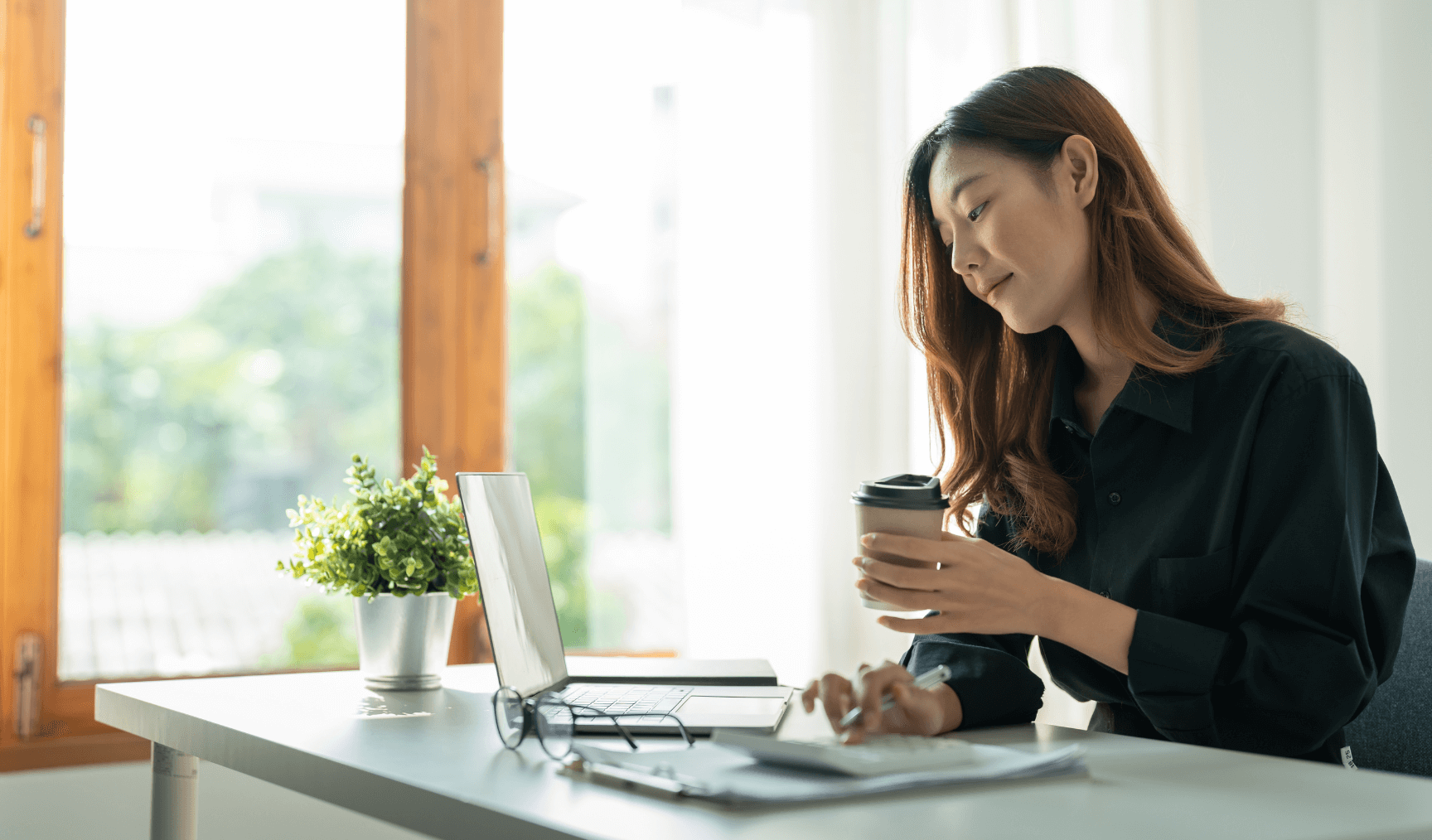 woman at her work desk holding a cup of coffee