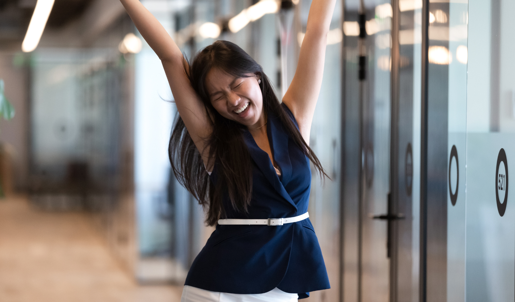 woman raising her hands in glee in the office