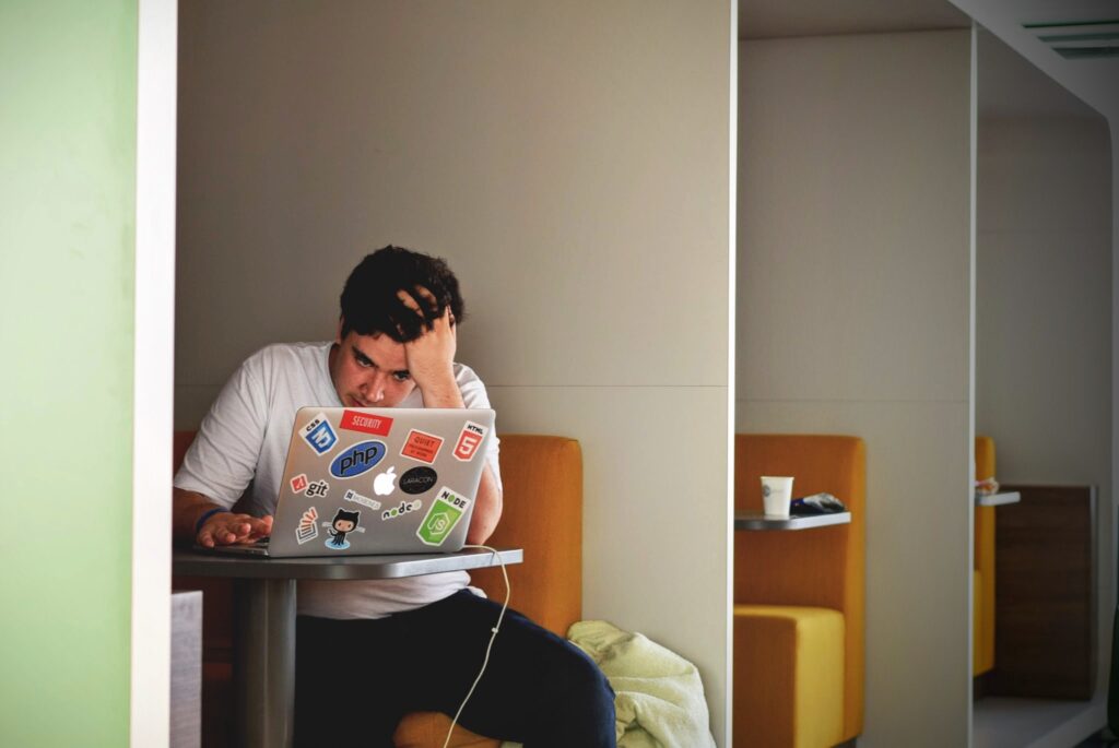 Man holding his head and looking at his laptop