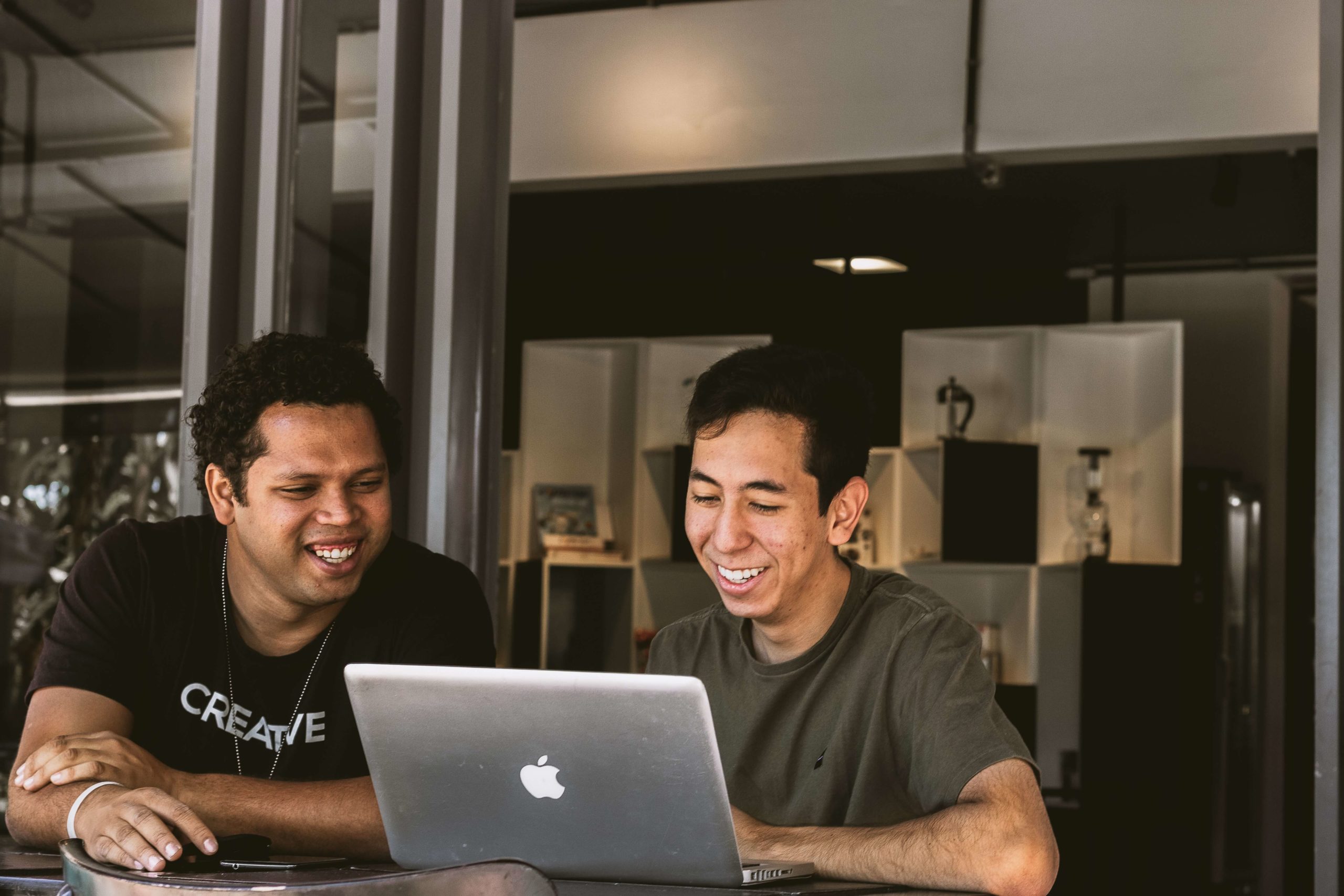 two men smiling at the laptop