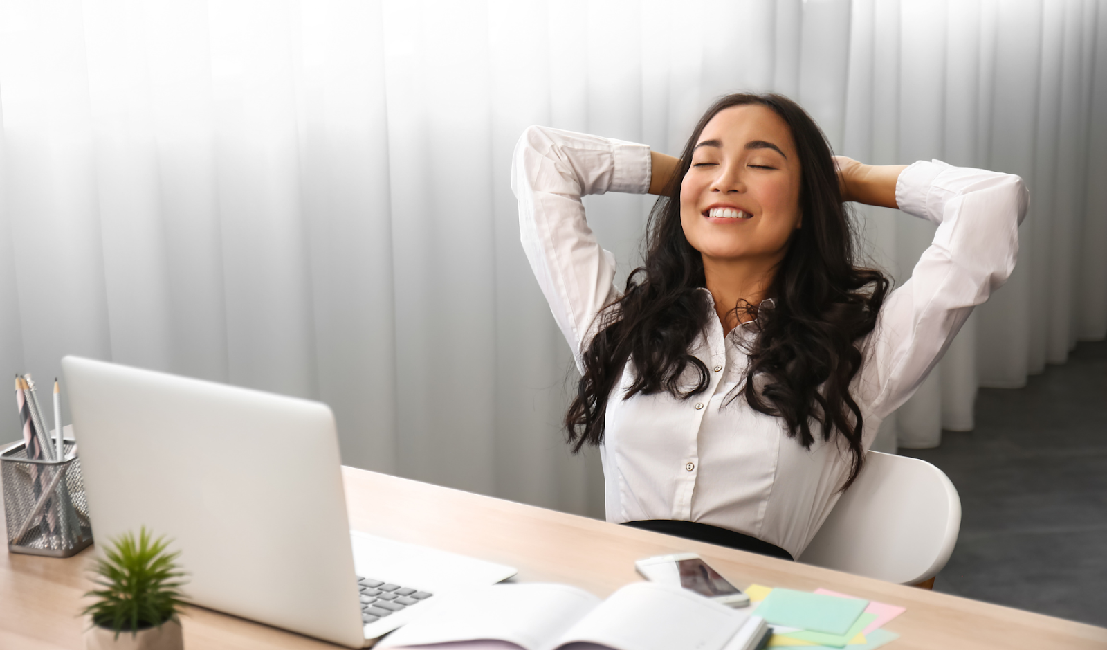 woman smiling and leaning back in her chair in front of a laptop