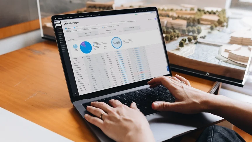 “Person working on a laptop displaying a utilization target dashboard with charts and data tables.”