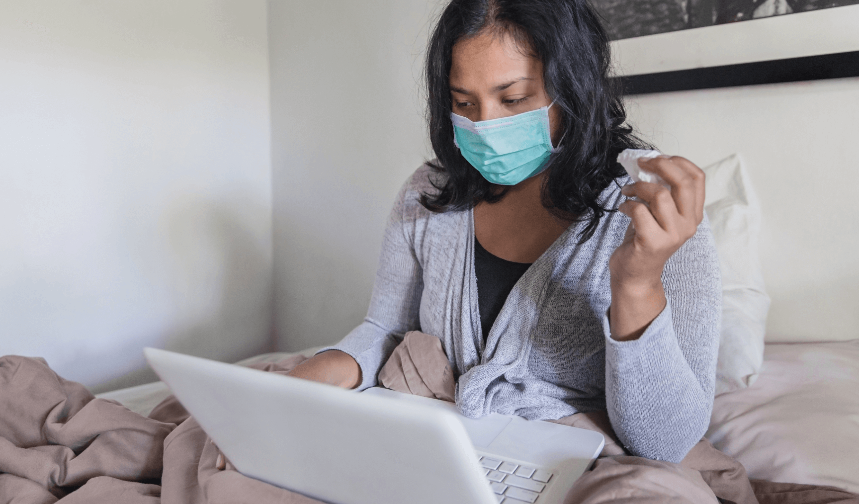 sick employee using her laptop in bed