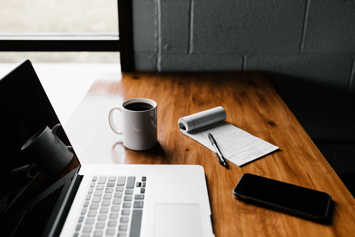 computer, cup of coffee and notepad on desk