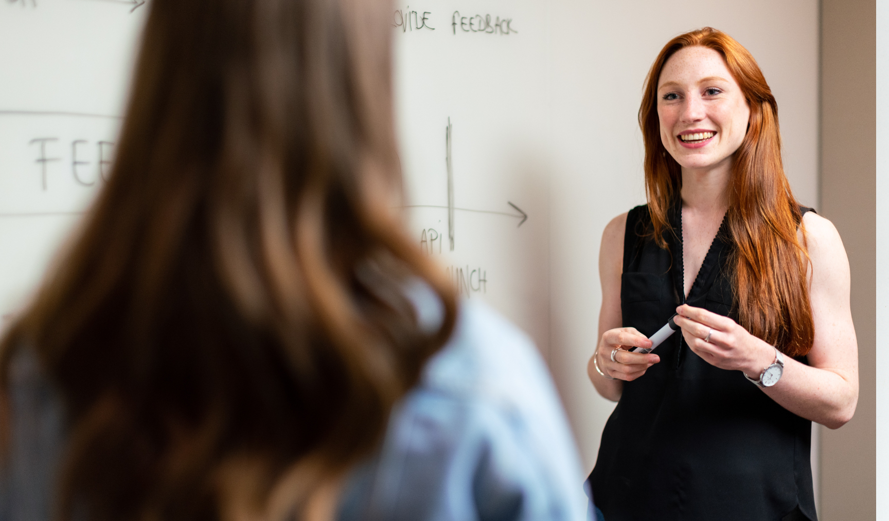 Woman stands at a whiteboard, discussing ideas