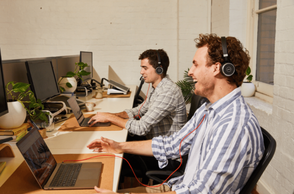 Two men working on laptops laughing