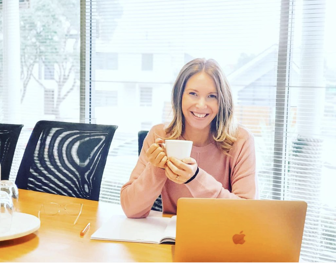 Person sitting at laptop, holding a cup of tea