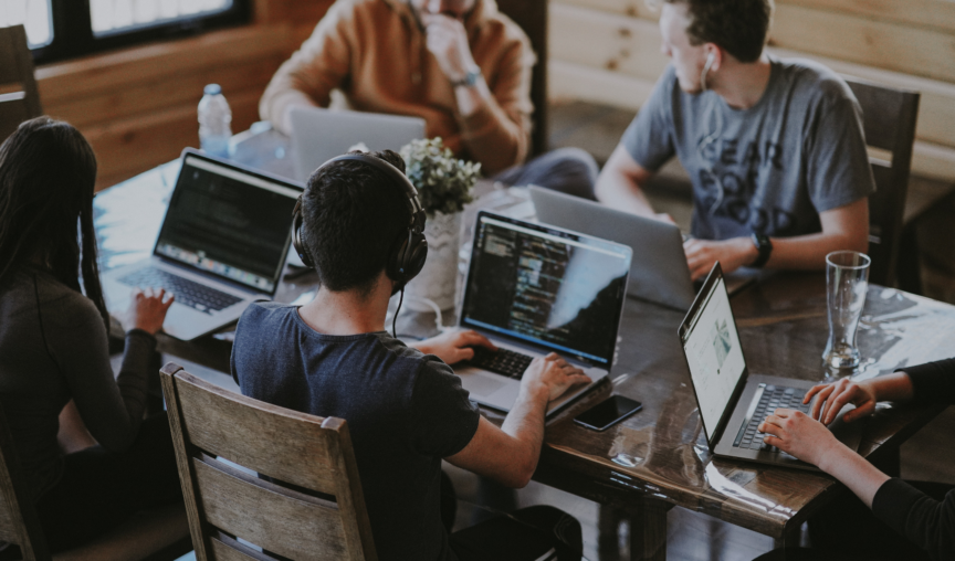 A group of people sitting at a shared table on their laptops