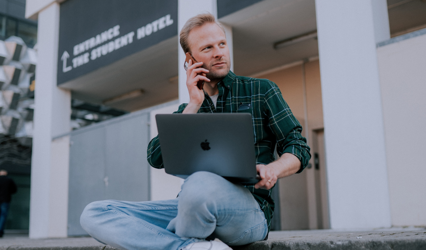 Man on the phone while he sits, browsing his laptop