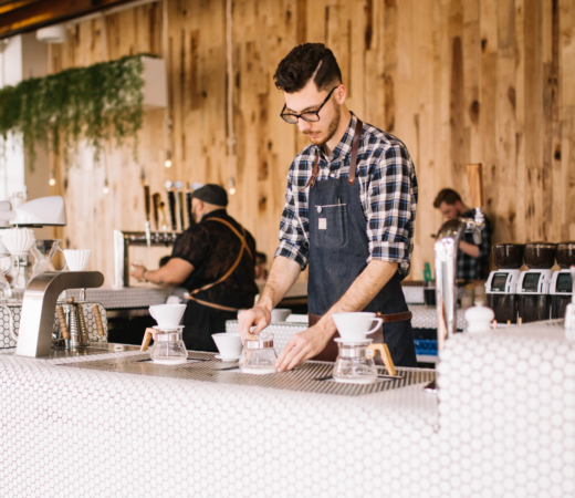 Barista stands behind counter, setting out coffee pots