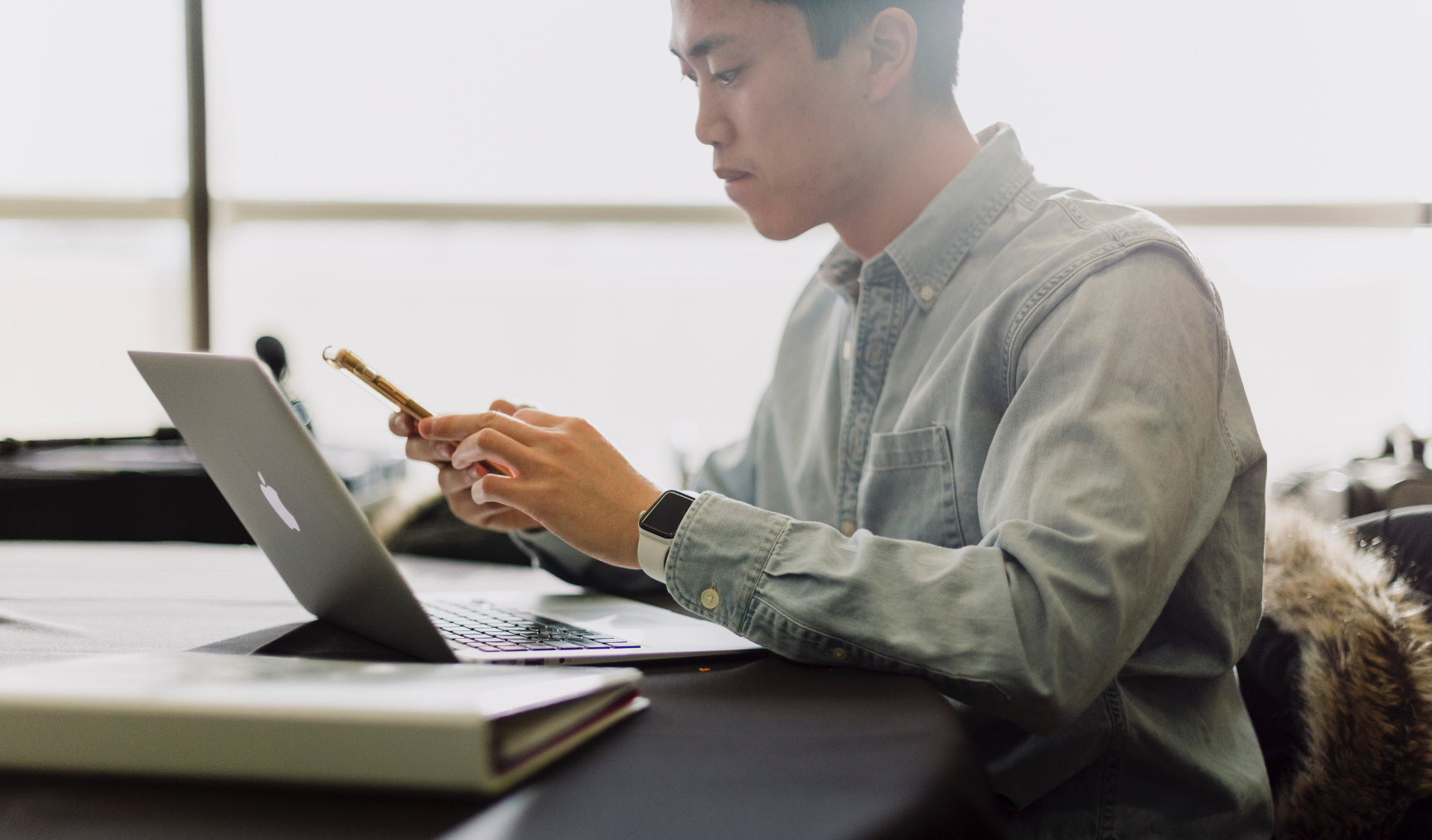 Man looks at his phone at a desk, with a serious expression