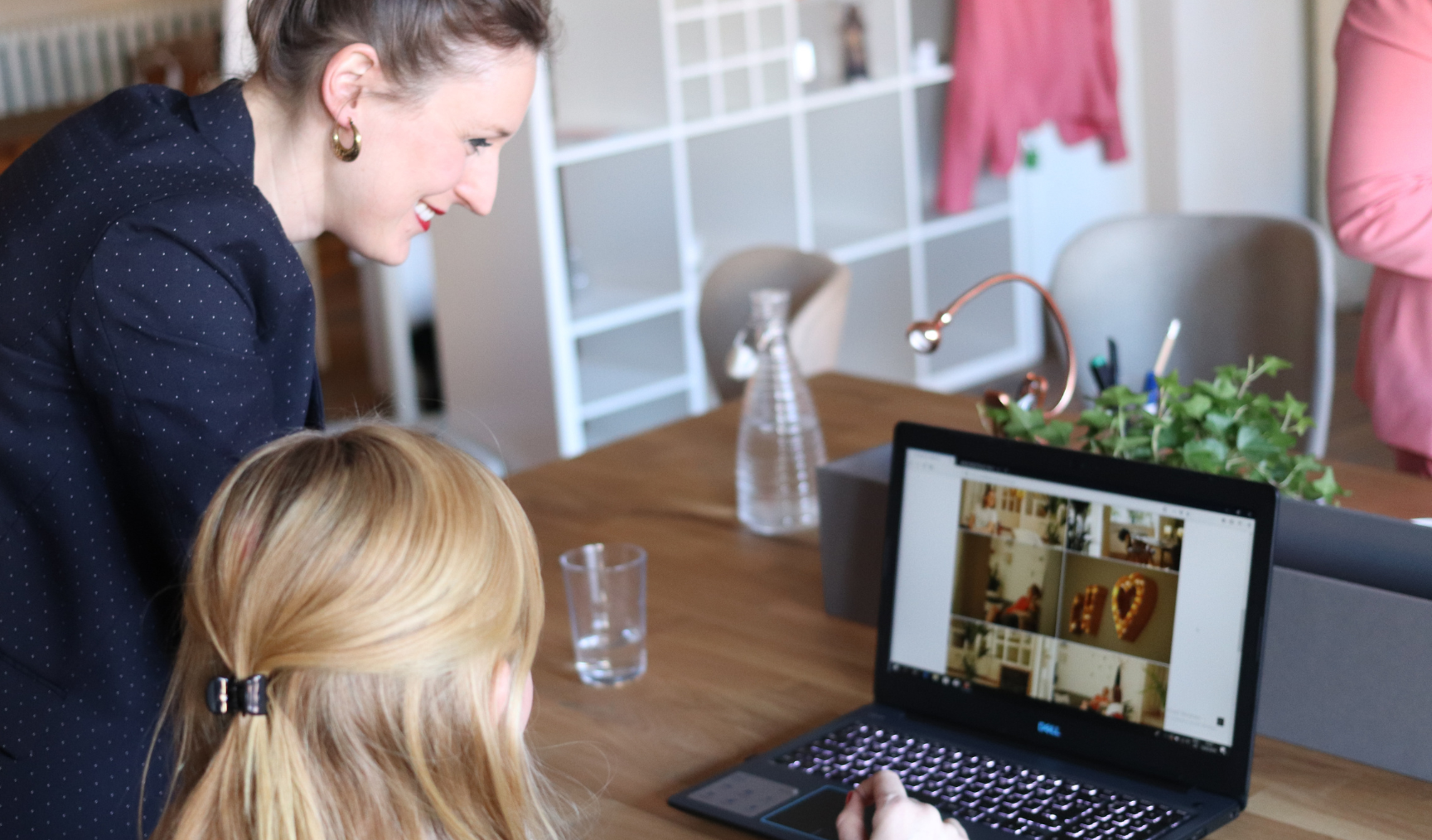 Two women look at a laptop gently smiling at the screen