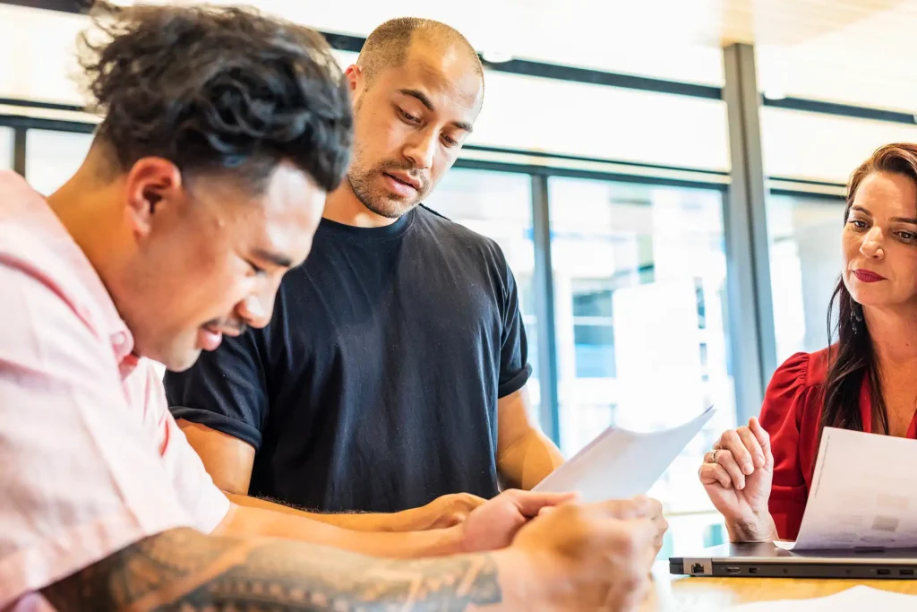 Three professionals reviewing documents together in a modern office setting.