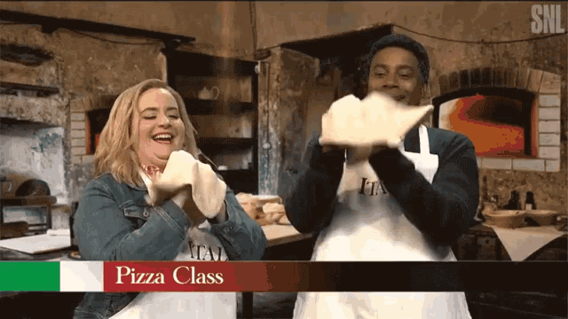 Two people stand in a cooking class, tossing pizza dough