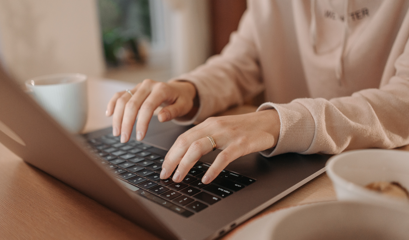 A woman types on a laptop, only hands visible