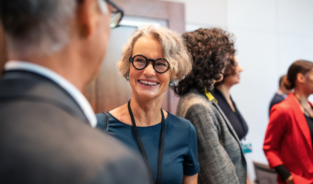 A woman stands in a conference, chatting to her peers