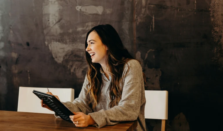 Woman smiling as she's holding an tablet